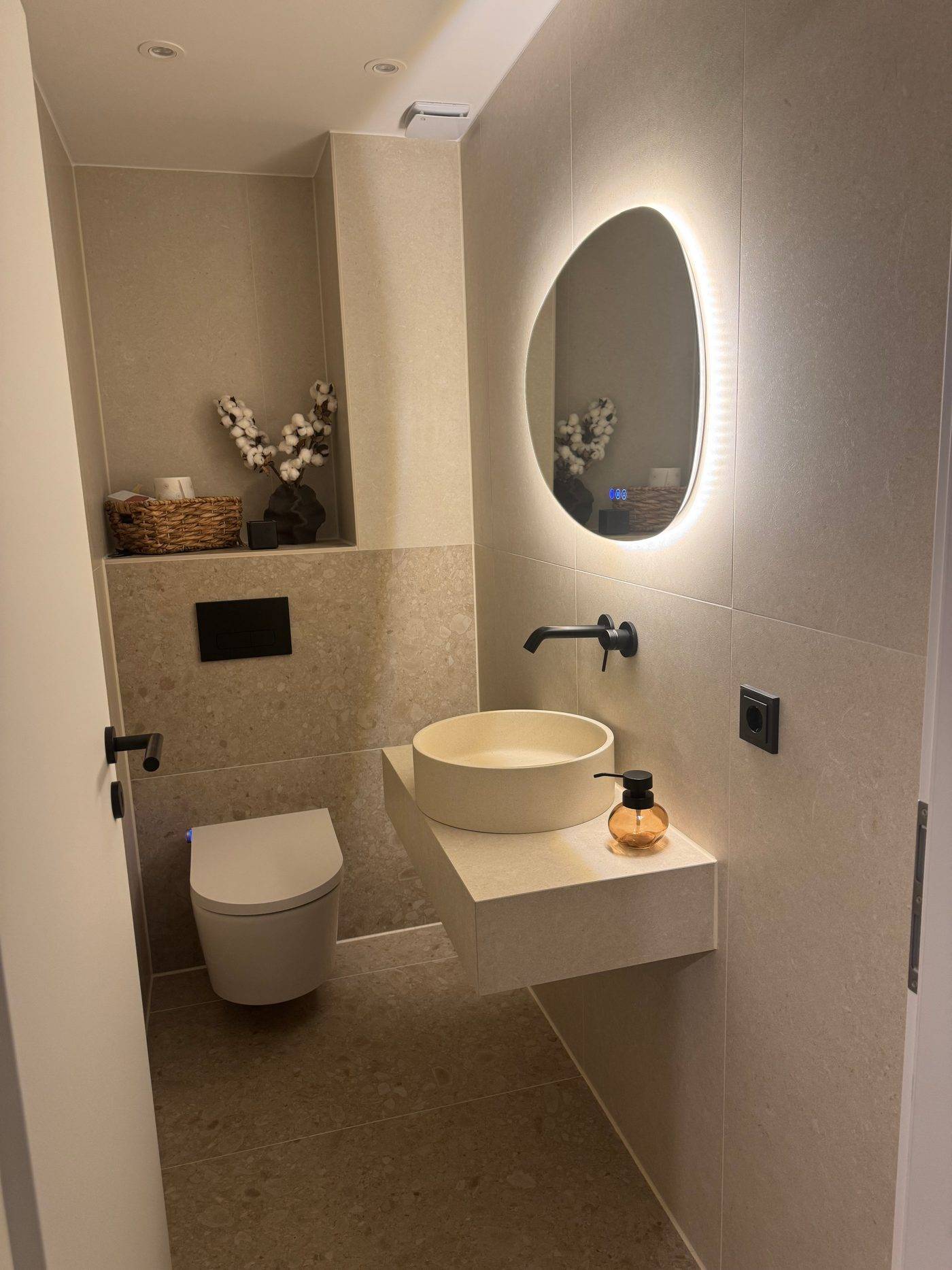 Gäste-WC mit XXL-Kalksteinoptik, beleuchteter Wandnische und rundem Aufsatzbecken