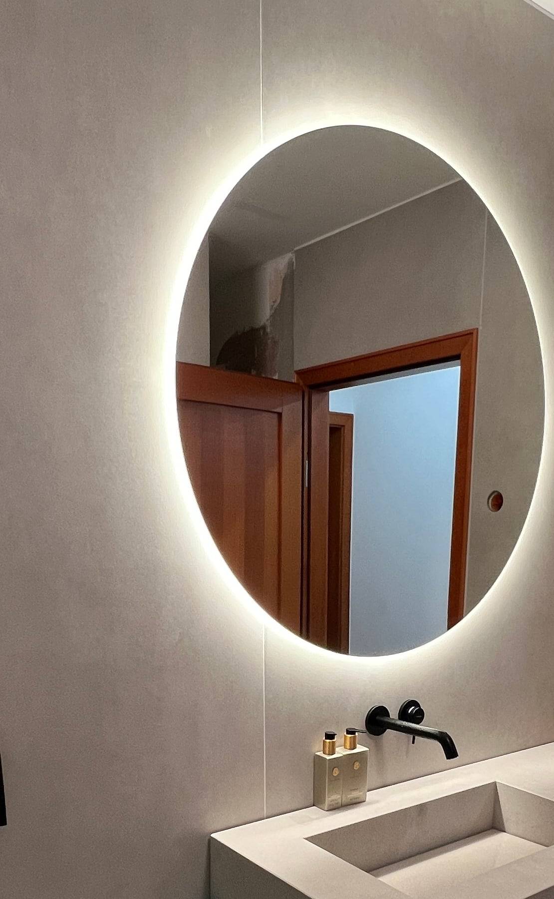 Gäste-WC in Betonoptik nach einer Bestandssanierung mit beleuchtetem Rundspiegel