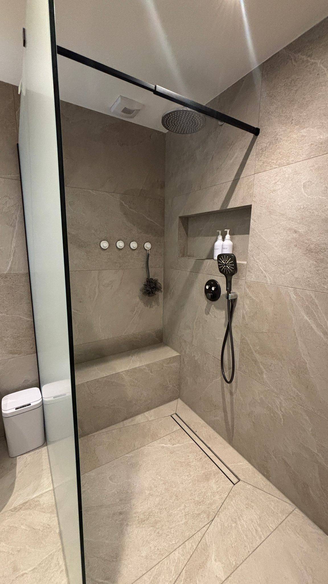 Geflieste Dusche in Steinoptik mit Sitzbank, Ablagenische und schmalen Fugen