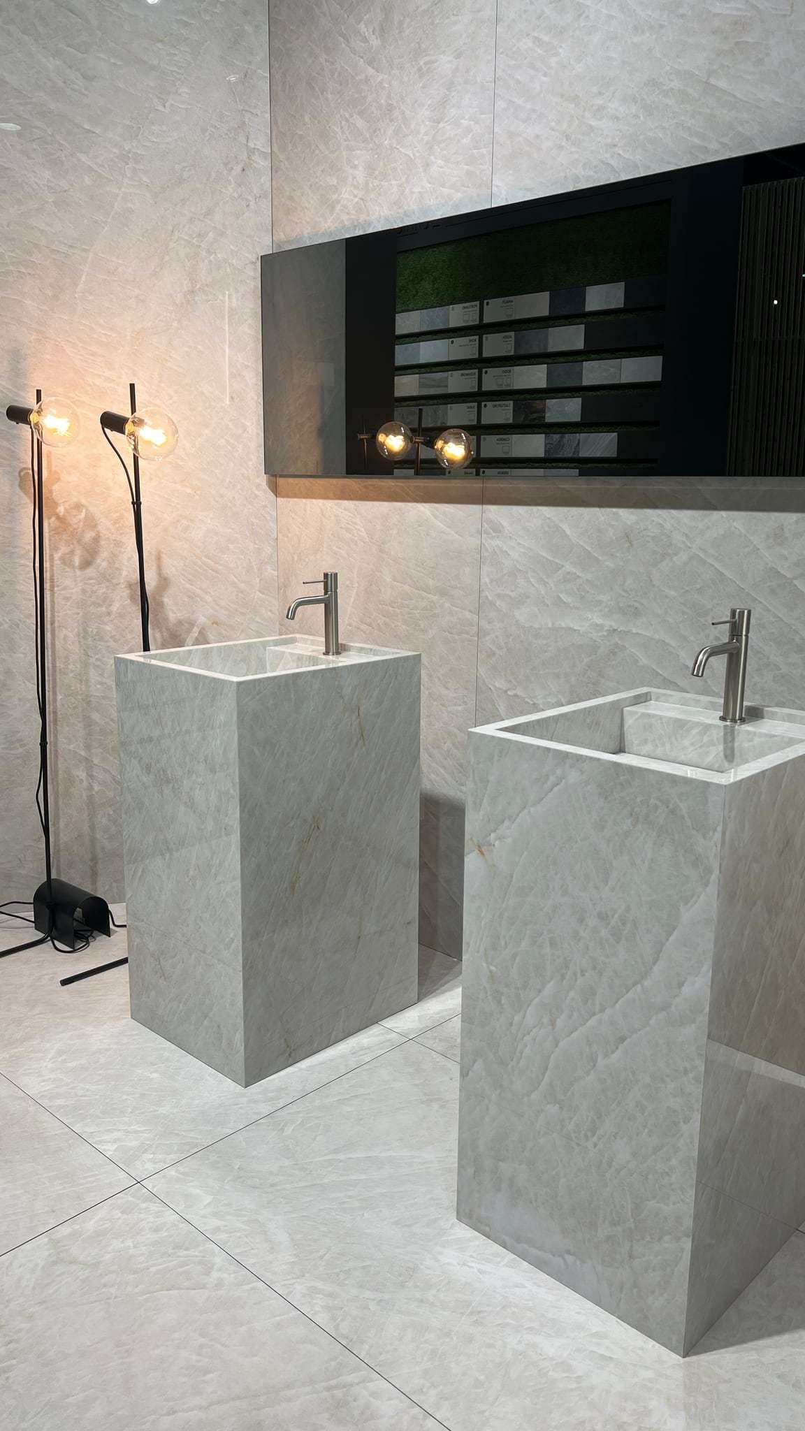 Zwei freistehende Säulen-Waschtische aus Keramik in Marmoroptik mit Edelstahl-Armaturen im Showroom